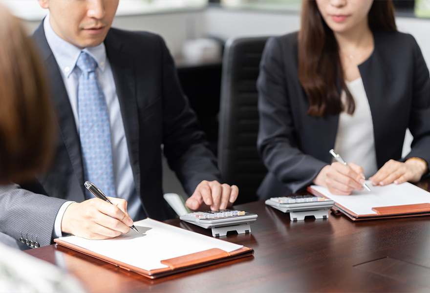 電卓を打つスーツ姿の男女